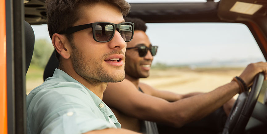 Smiling young male friends driving a car