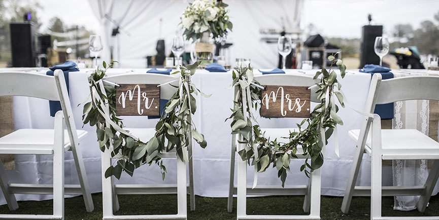 Wedding table under tent, with Mr and Mrs signs on the chairs